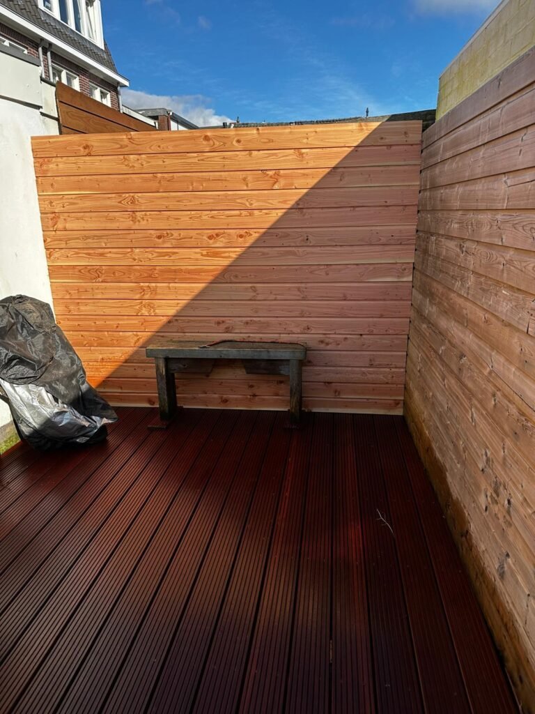 Houten tuinafscheiding met horizontale planken en een houten vlondervloer in een compacte stadstuin