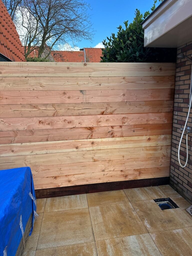 Houten tuinafscheiding met horizontale planken bij terras en gevel