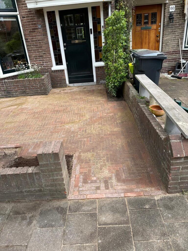 Voortuin met bestaande klinkerbestrating in visgraatpatroon bij een woning met bakstenen gevel