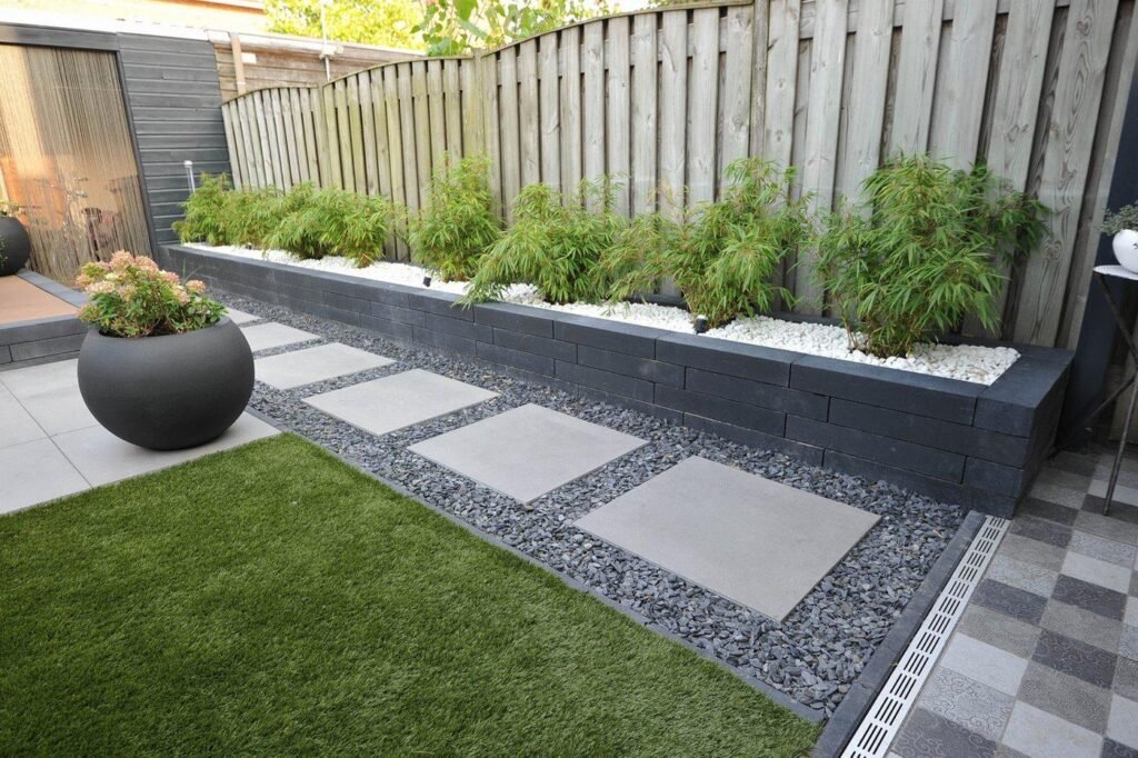 Moderne tuin met strakke bestrating, verhoogde plantenbak, grindpad en houten tuinafscheiding